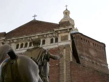 Back view of the Regisole bronze equestrian statue with a brick cathedral facade behind it.