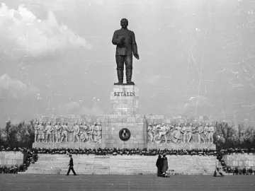 Stalin Monument in Budapest with a towering statue on a large pedestal and socialist realist bas-reliefs below.