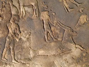 Section of the Dendera Zodiac showing carved human figures beside a large animal figure on a stone relief.