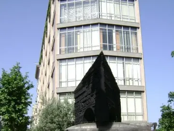 Monument to Narcís Monturiol with a bronze submarine model on a dark geometric pedestal beside a city street.