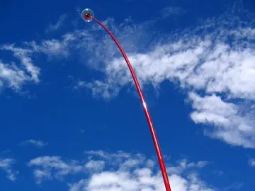 Wind Wand sculpture curving upward against a blue sky with scattered clouds.