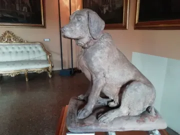 Cane Tago, a seated terracotta dog sculpture with a faint red collar.