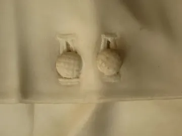 Close-up of two intricately carved spherical elements set in a light surface recess.