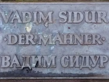 Bronze plaque for Der Mahner by Vadim Sidur with raised Latin and Cyrillic lettering.