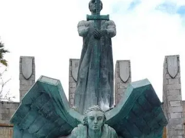 Monumento a Franco with a robed figure holding a cross-hilt sword above a winged figure on a stone base.