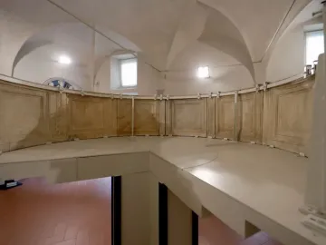 Reconstructed structure of the Pulpit of Prato Cathedral with a curved paneled railing inside a vaulted room.