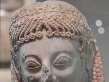 Marble head of the Rampin Rider with an archaic smile, carved curls, and a decorative leaf-pattern band.