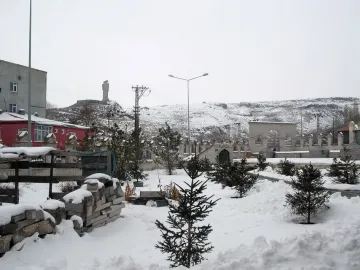 Statue of Humanity with two upright figures reaching toward each other on a snowy hilltop