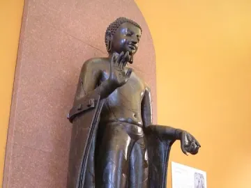 Sultanganj Buddha sculpture with raised right hand and outstretched left arm on a raised platform.