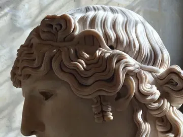 Left-side profile of the Antinous Mondragone marble head with wavy hair and a calm expression.