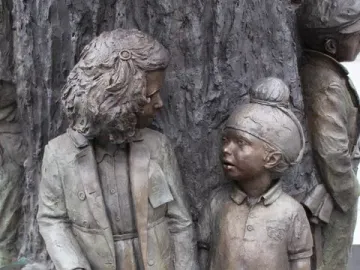 Bronze children figures beside the textured tree trunk of the Betty Campbell statue.