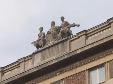Three-figure Music sculpture on a rooftop, with a seated woman in the center, a figure holding an animal on the left, and a musician on the right.