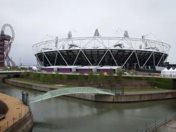 The Orbit Tower rises in a twisting reddish-brown steel structure against a bright overcast sky.