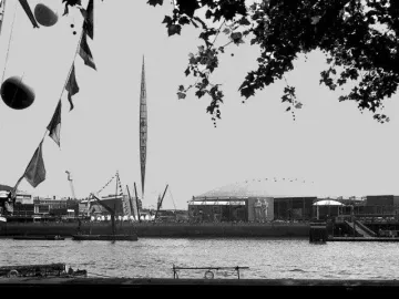 The Skylon, a tall slender pointed framework structure, rises against a bright sky.