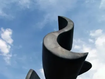 Ayrton Senna Monument bronze sculpture silhouetted against a blue sky with wispy clouds.