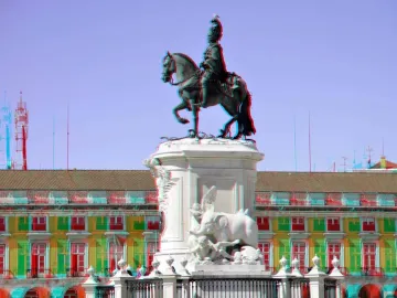 The Equestrian Statue of Joseph I on a white stone pedestal in a public square, with a grand archway and yellow buildings behind it.