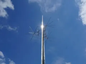 Ad Astra sculpture with a tall metallic spire and radiating spikes against a blue sky.