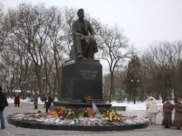 Chekhov Monument with a seated bronze statue on a stone pedestal in a snowy park