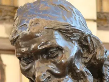 Dark bronze bust of Eustache de Saint Pierre showing an elderly bearded man in a cap looking downward.