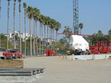 Levitated Mass boulder wrapped in white plastic on a transport vehicle at a construction site.