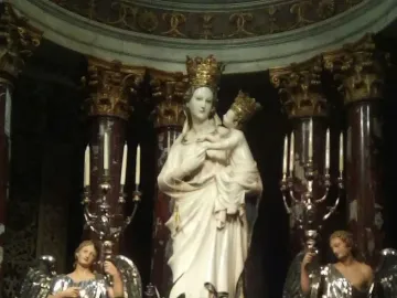 Crowned Madonna di Trapani statue holding the child, flanked by silver-clad angels with lit candelabras.
