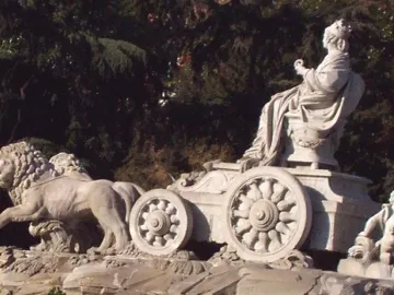 Cibeles Fountain sculpture with a crowned figure seated in a chariot pulled by two lions.