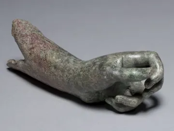 Weathered bronze arm and hand from The Cleveland Apollo with a green and reddish-brown patina.