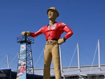 The Golden Driller statue stands with one hand on an oil derrick and one hand on his hip in Tulsa.