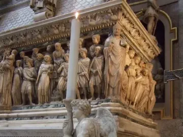 Michelangelo’s Angel sculpture shown kneeling and holding a tall candle on the Shrine of Saint Dominic.