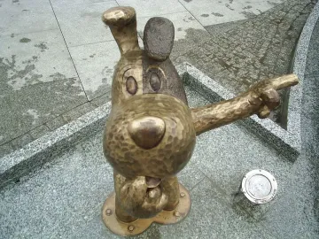 Bronze Reksio monument showing a stylized dog sculpture pointing its right arm.