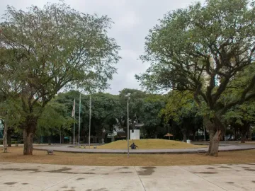 Ayrton Senna Monument on a raised grassy mound in a park, with a paved circular path and trees around it.