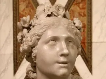 Blessed Soul, a white marble bust of a female figure with curly hair and a flower wreath, shown on a veined marble pedestal.