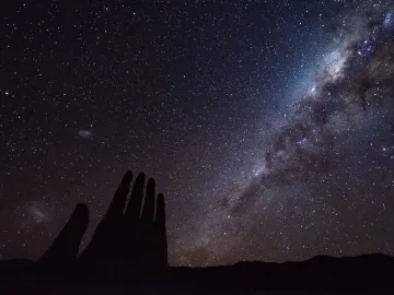 The Mano del Desierto sculpture silhouetted against a star-filled night sky and the Milky Way.