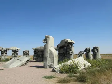 Inner circle of Carhenge with vintage cars painted gray and arranged in a sandy field.