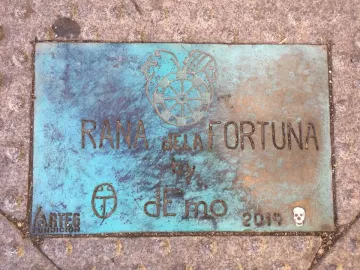 Rusty bluish-green plaque for Lucky Frog with engraved text and symbols.