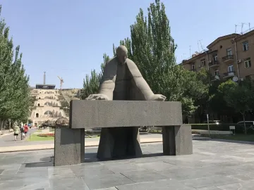 Monument to Alexander Tamanyan in a paved plaza, with a large stone staircase rising behind it.