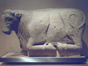 Bull of Osuna stone sculpture shown in profile on a white plinth.