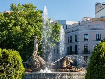 The Fountain of Neptune in Madrid with Neptune standing on a shell, flanked by two sea-horse figures and surrounded by jets of water.