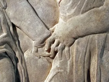Detail of the Pulpit of Prato Cathedral showing carved hands amid draped folds in stone relief.