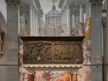 The Passion Pulpit, a dark bronze pulpit with densely carved relief panels and crucifixion scenes, set against a painted architectural backdrop.