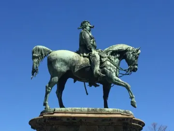 Victor Emmanuel II Monument showing a dark metal equestrian sculpture against a clear blue sky.