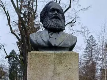 Karl Marx Monument showing a dark bust of a bearded man on a tall stone pedestal.