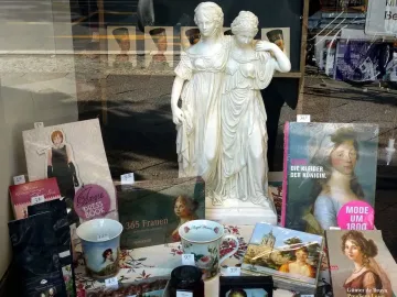 Princesses Monument statue displayed in a bookstore window among books and other merchandise.