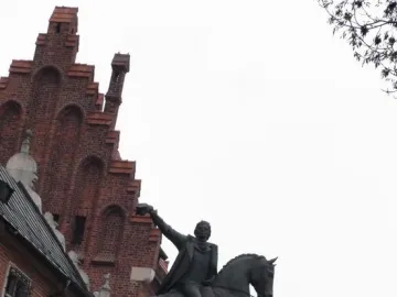 Tadeusz Kościuszko Monument, a dark equestrian statue of a man in a long coat with one arm raised, against a bright overcast sky.
