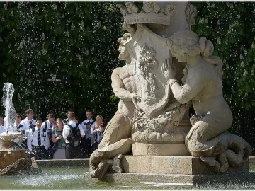 Fountain of the Artichoke with stone figures holding a crest in a pool of water.