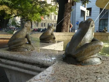 Three bronze frog sculptures on the Fountain of the Frogs spouting water from a stone basin.