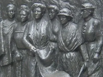 Close-up of the Kate Sheppard National Memorial bronze relief showing women in period clothing around a scroll and small wheeled cart.