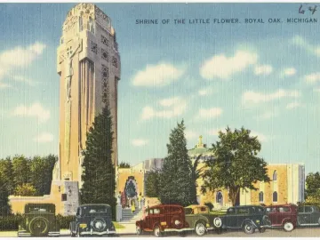 National Shrine of the Little Flower with a tall ornate tower, crucifix relief, and cars parked along the street below.