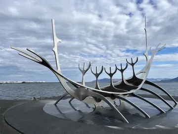 The Sun Voyager sculpture beside calm water under a cloudy sky.
