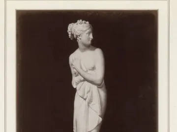 Venus Italica standing marble statue with draped cloth, turned to the right on a round pedestal.